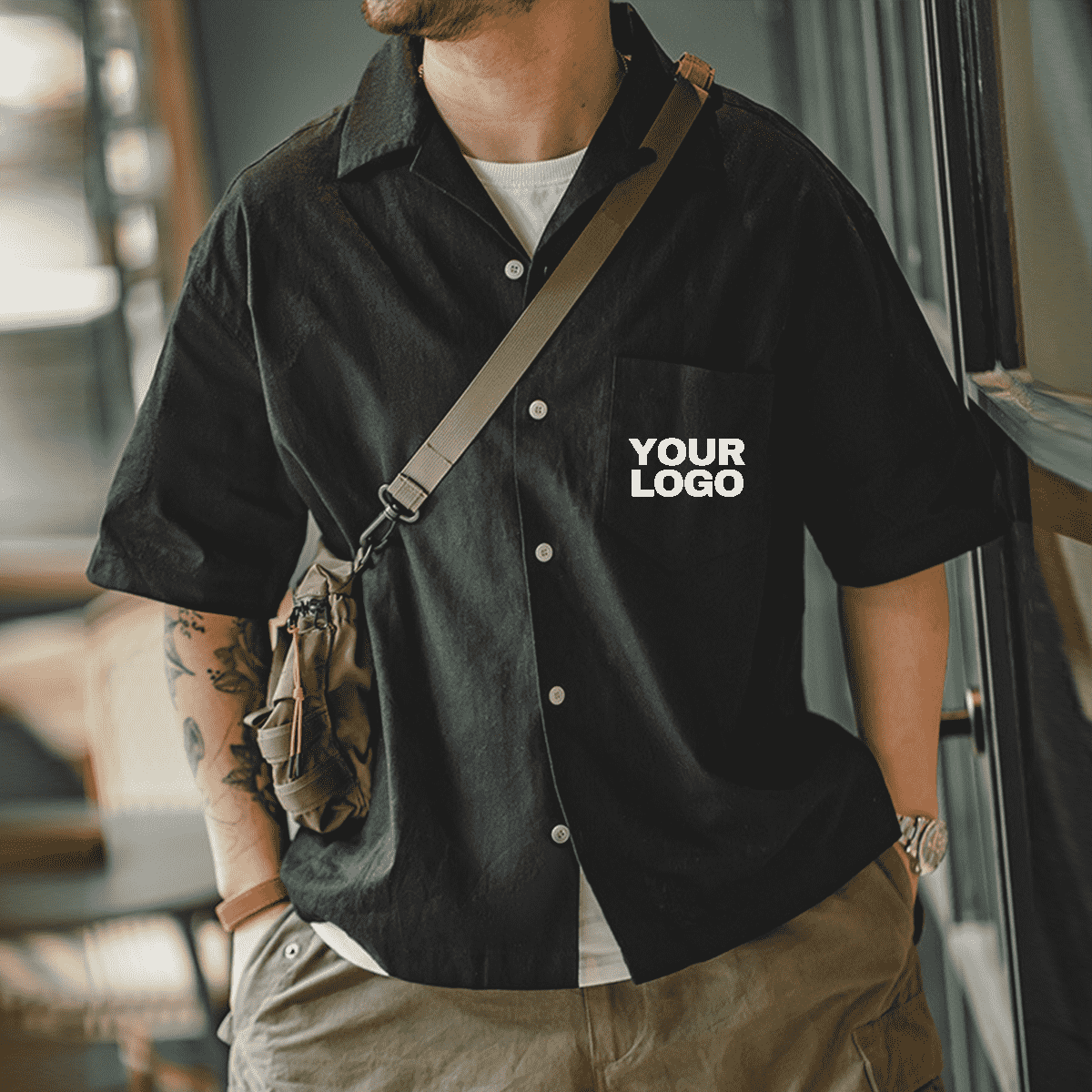 Homme portant une chemise noire à logo personnalisé, style pro décontracté, tenue pour team ou événement