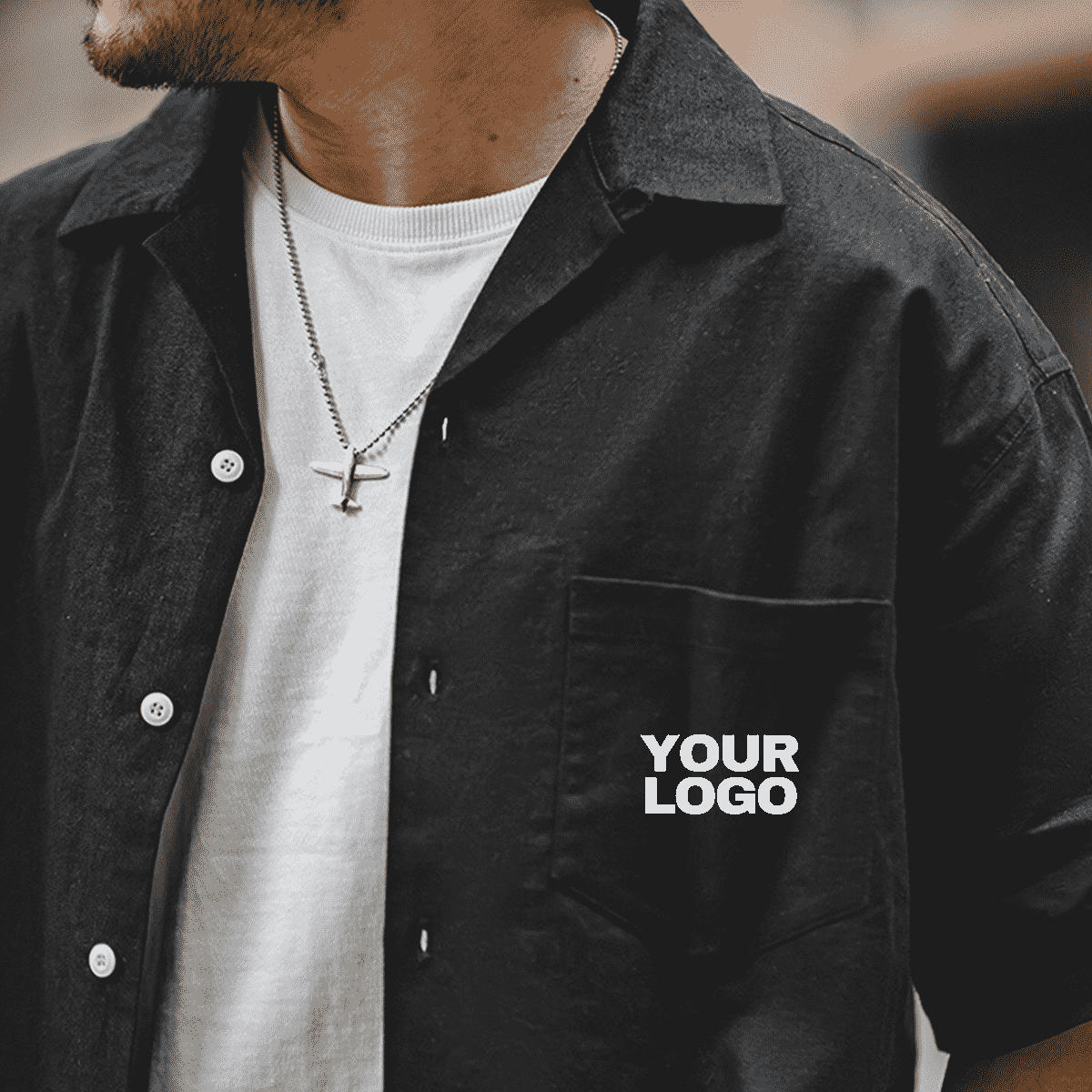 Détail visuel d’un logo personnalisé imprimé sur une poche de chemise noire, textile pro